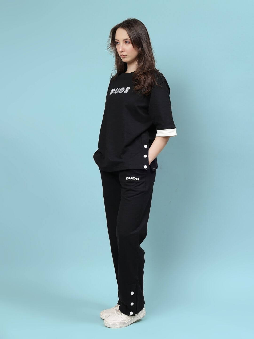 Woman wearing WOMEN'S WESENT RELAXED-FIT CO-ORD SET BLACK, featuring heavy gauge fabric and cotton elastane blend, standing against blue background