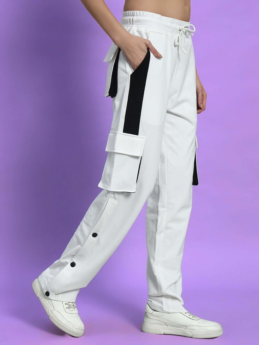 Side view of Women's Bracket Cargo Pant White Black Highlighter, featuring multiple pockets and vibrant accents, against a purple background.
