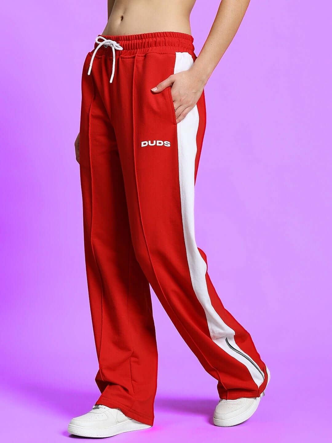 Women's Wonder Slit Zipper Joggers in Red-White by DUDS with side pockets and elastic waistband, shown on a model with purple background.