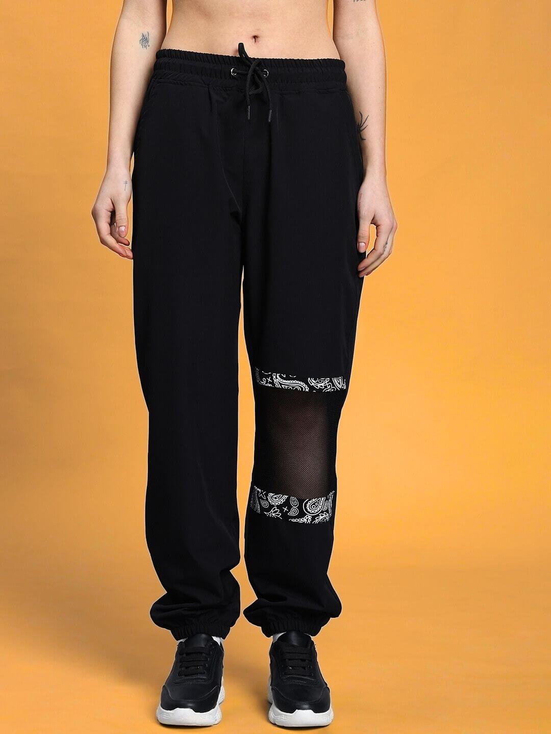 Woman wearing black relaxed fit cargo pants with elastic waistband and drawstring, showcasing casual style on a warm-toned background.