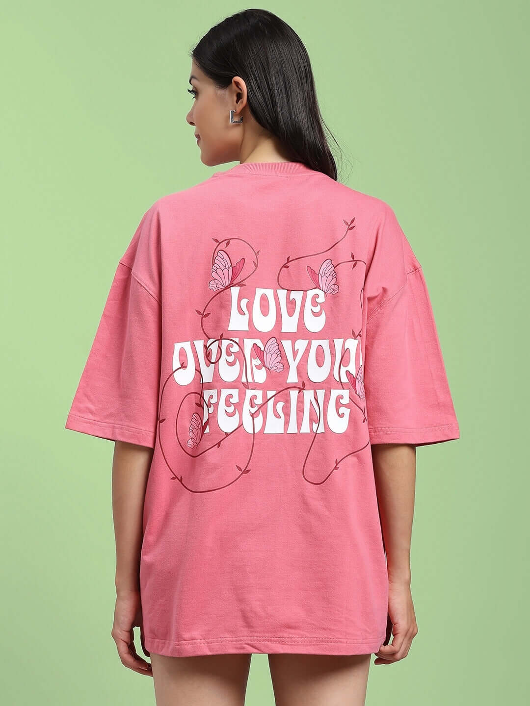 Back view of women's pink printed T-shirt with 'Love Your Feeling' design, made of premium cotton blend, worn by a model.