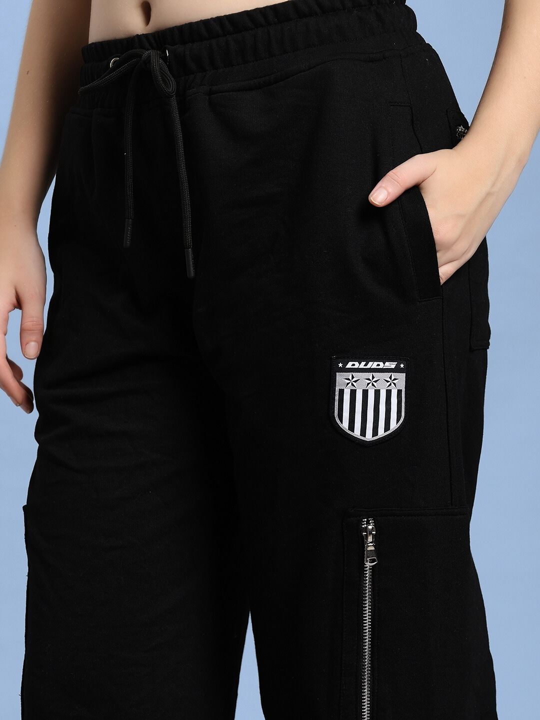 Close-up of WOMEN'S ZIP TECH PREMIUM CARGO BLACK pants with zip pocket detail, showcasing sleek black design and urban utility style.