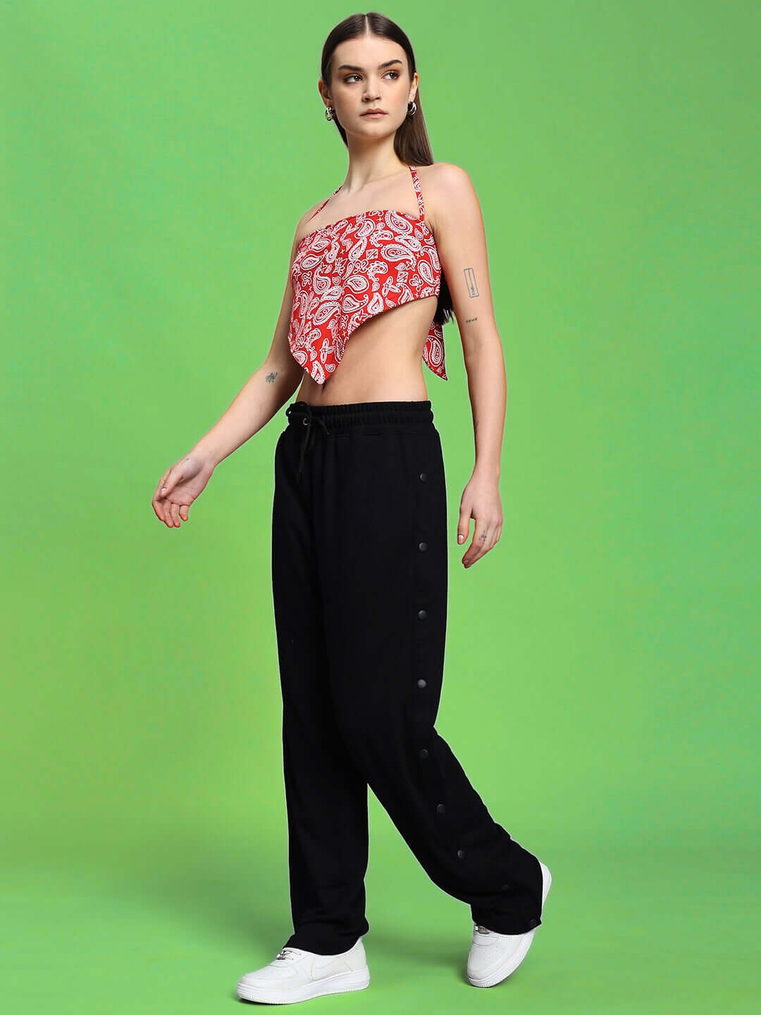 Woman wearing red-black Ziva co-ord set with relaxed joggers, elastic waistband, and paisley top, against a green background.