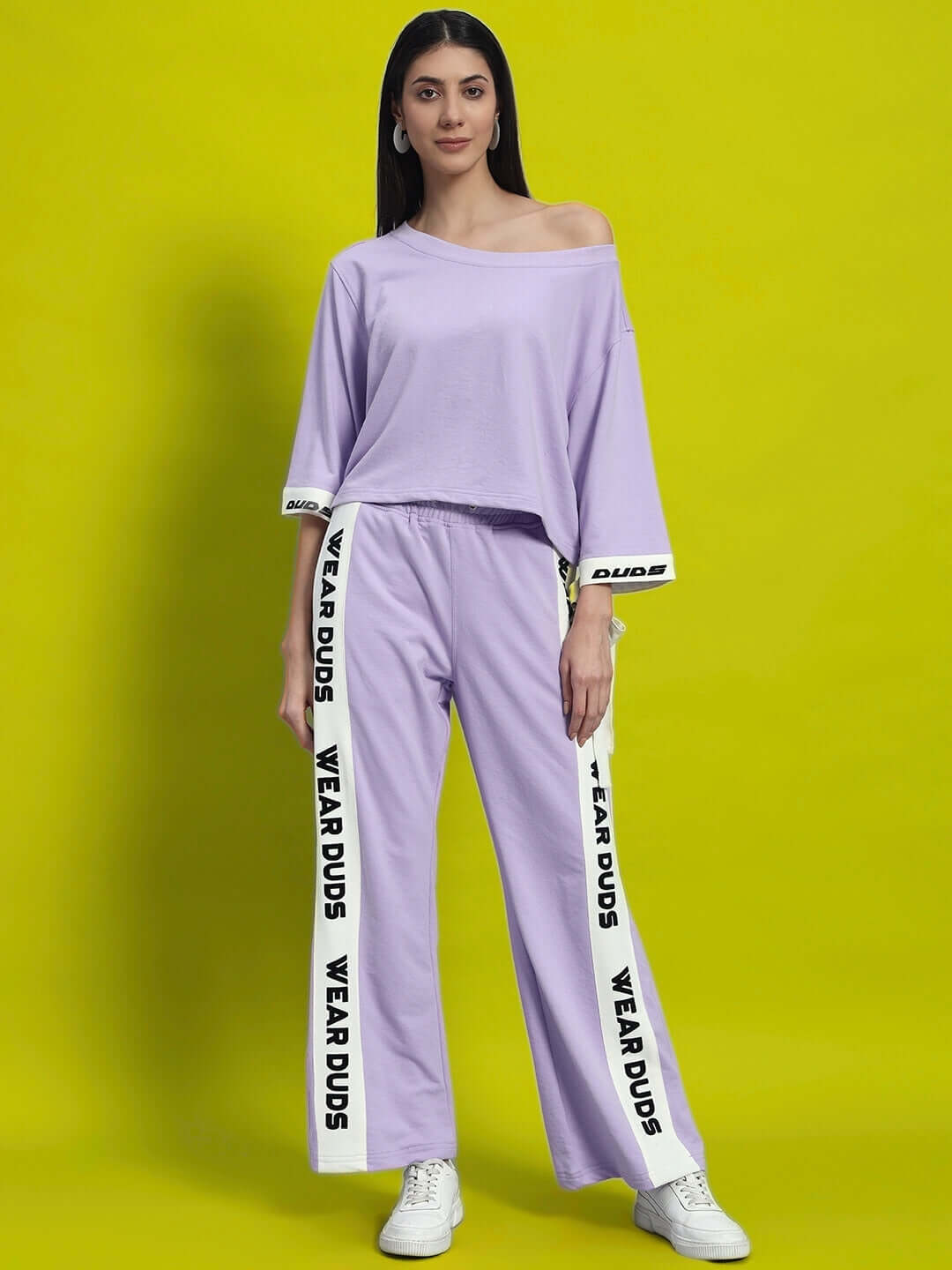 Woman wearing lilac aroma co-ord set with relaxed fit joggers, premium cotton fabric, elasticated waistband, indoors, yellow background.