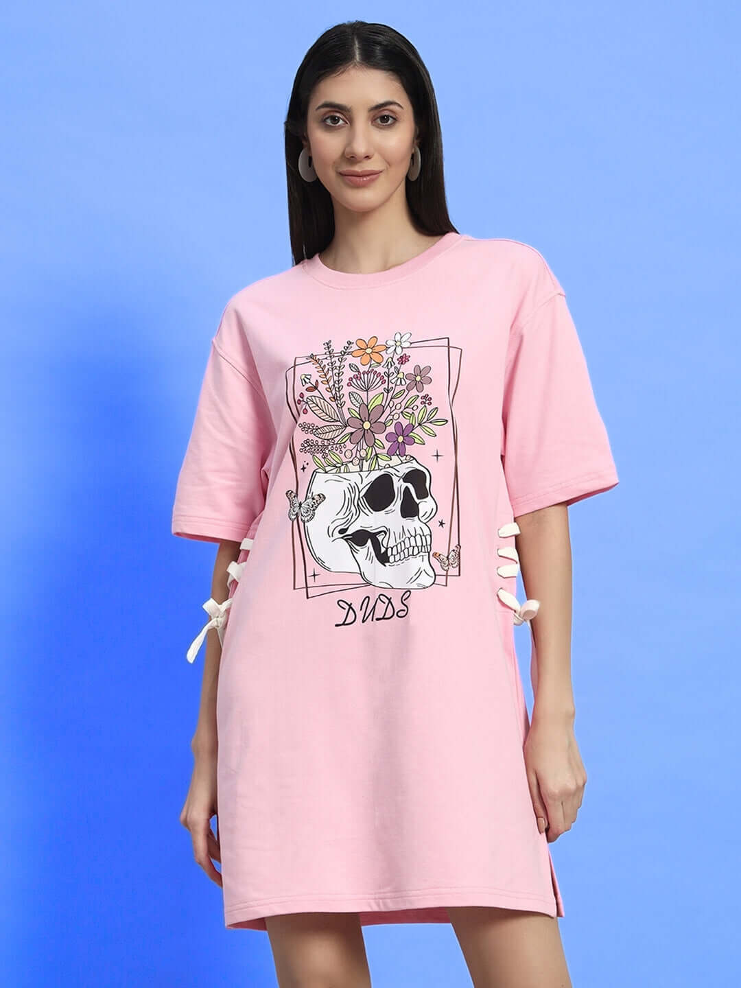 Model wearing baby pink women's sugar skull dress with floral design, made from 100% cotton, 240 GSM fabric, country of origin: India.