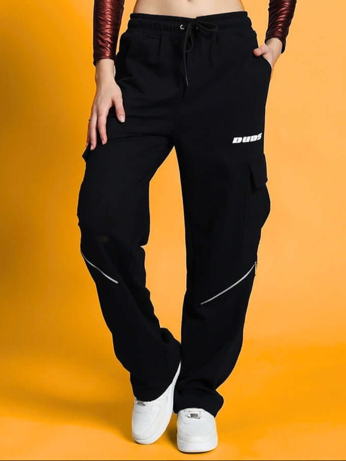 Model wearing WOMEN'S BRUNO 5 POCKET CARGO PANT BLACK with white sneakers on orange background
