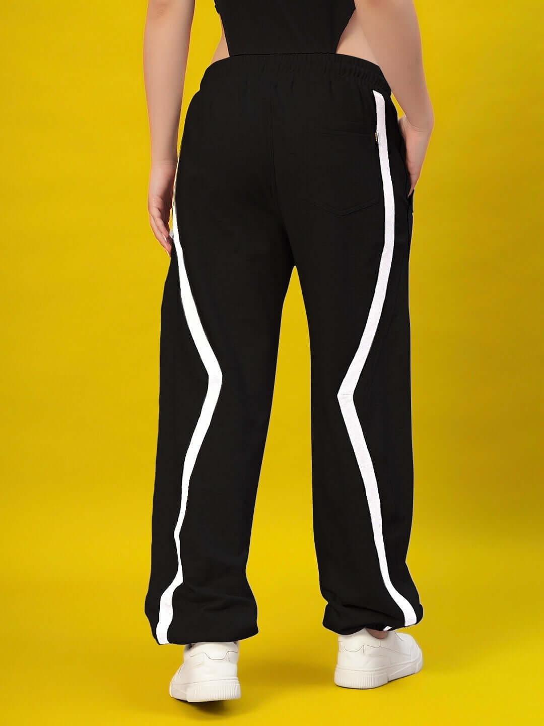 Back view of Women's DUDS Frame Joggers in black with white side stripes, showcasing casual style with a yellow background.