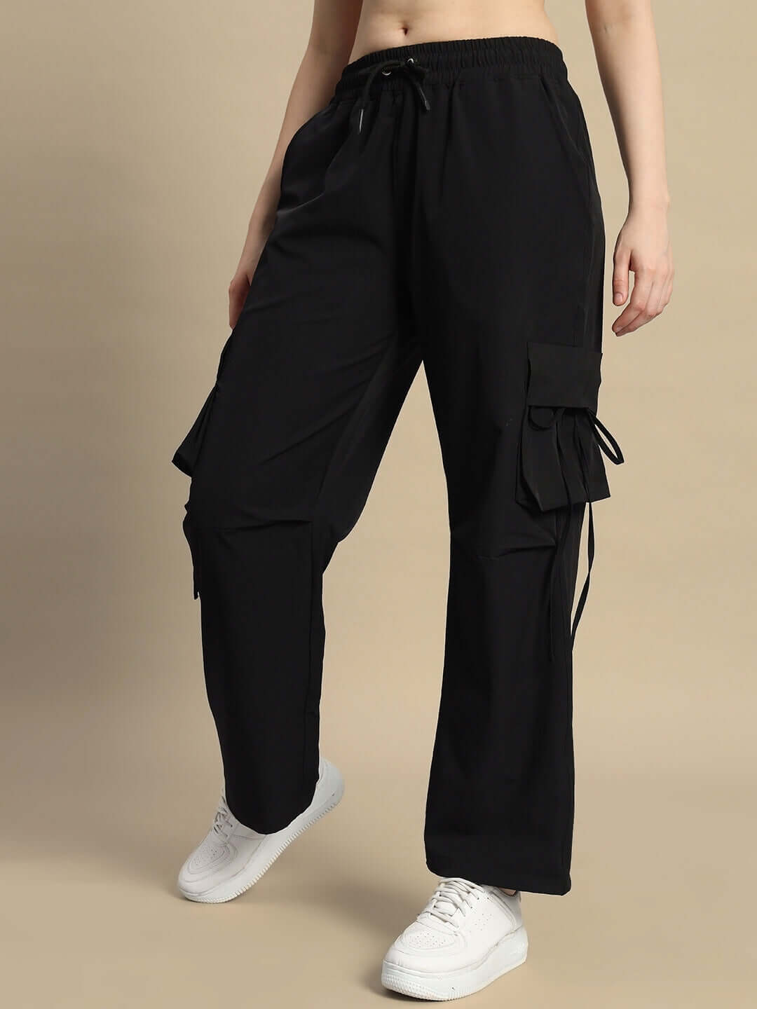 Woman wearing black Ramrod parachute cargo pants with drawstring waist and side pockets, paired with white shoes.
