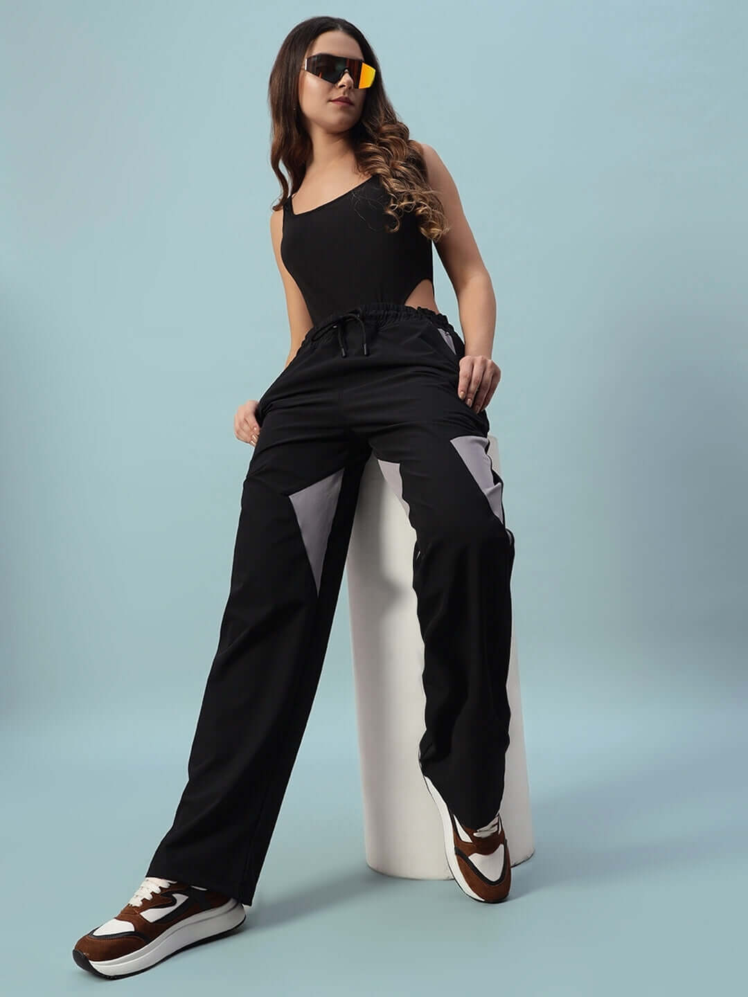 Model wearing women's Ranger relaxed fit black cargo pants with custom fit option, showcased with casual sneakers on a blue background.