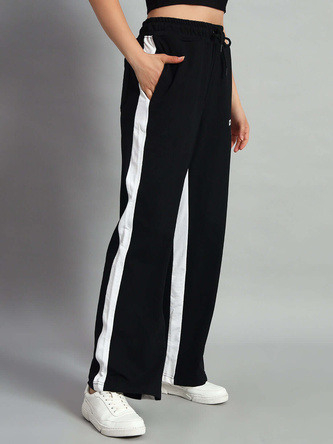 Black women's side seam baggy joggers with white stripes, shown with pockets, comfortable fit, styled with white sneakers.