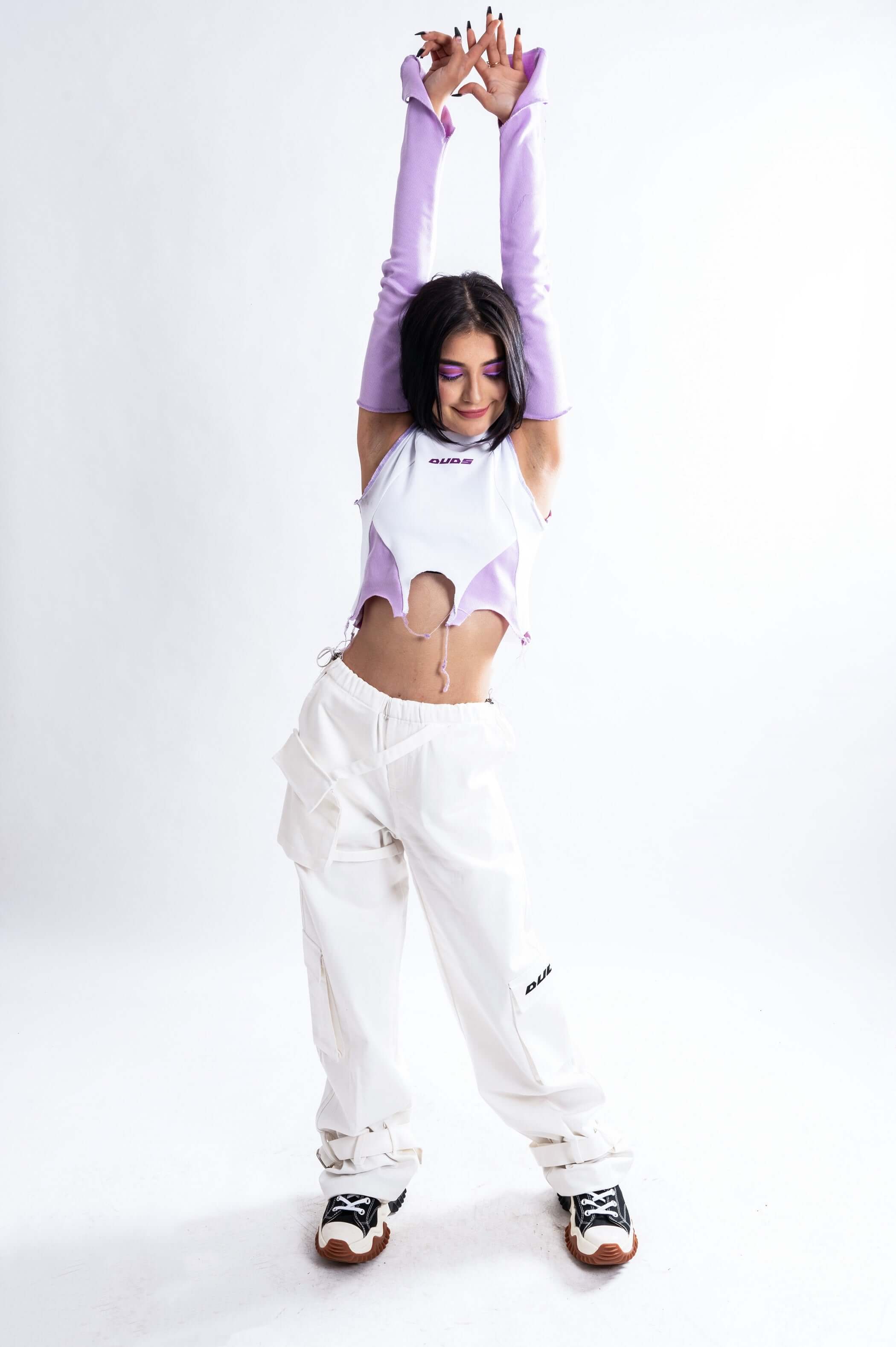 Woman wearing a stylish color block crop top with long sleeves and white pants, showcasing a modern and trendy look.