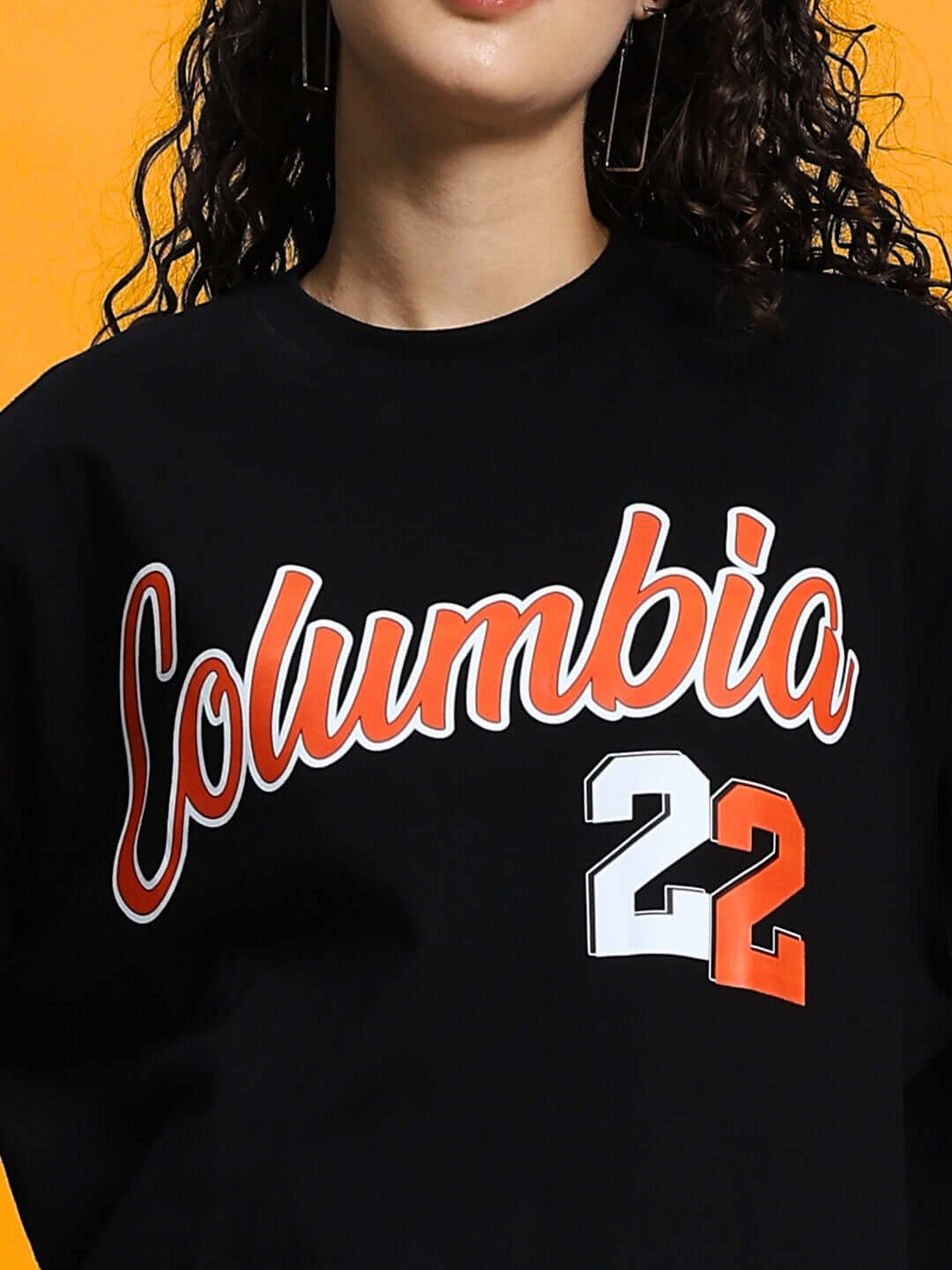 Woman wearing a black oversized Columbia 22 print t-shirt made of premium cotton and elastane, featuring a bold graphic design.