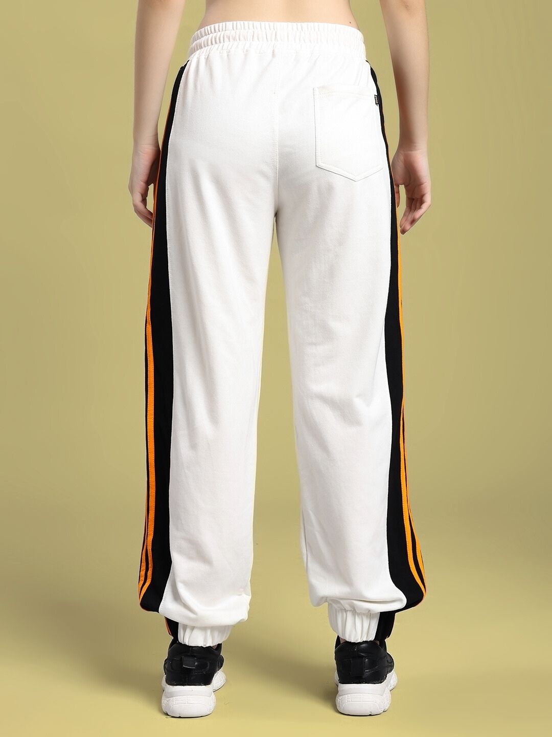Back view of WOMEN'S COMFORT FLEX STRIPE JOGGER OFF-WHITE with vertical stripe design, worn with black sneakers.