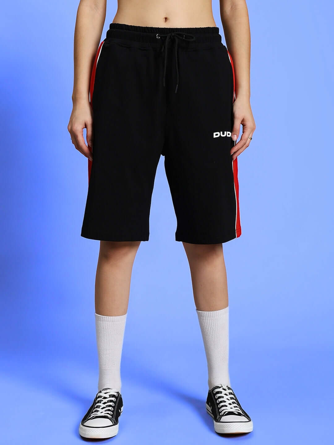 Model wearing WOMEN'S DRIFT REGULAR FIT SHORTS in black with side stripes and sneakers, showcasing casual style and custom fit option.