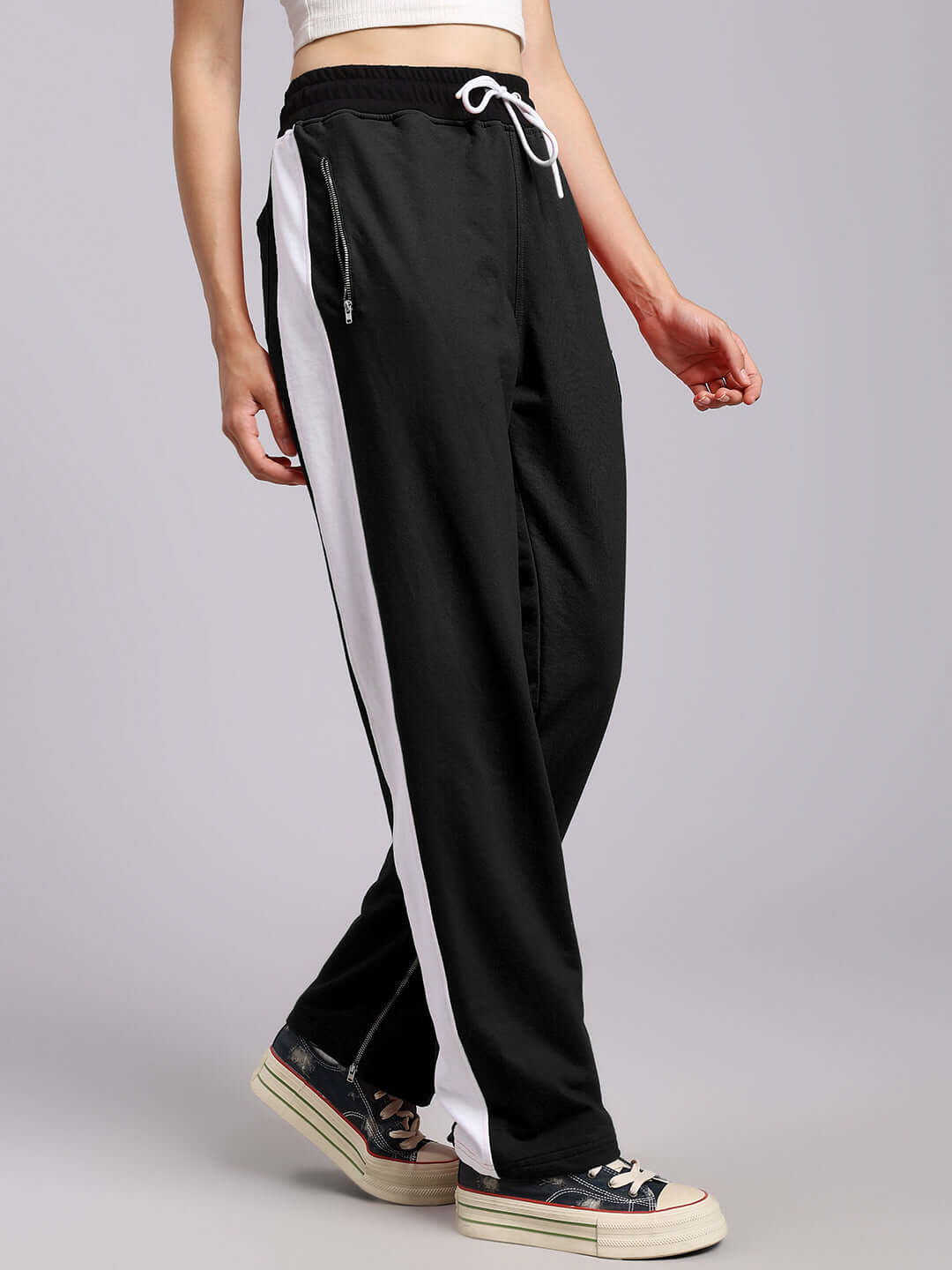 Women's elegant black relaxed-fit joggers with white side stripe, shown with drawstring waistband and casual style.