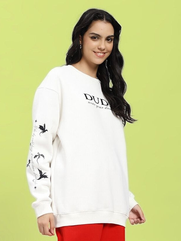 Model wearing WOMEN'S FLY OR DIE DRAGON PRINT FLEECE SWEATSHIRT OFF WHITE with dragon motif, showcasing bold streetwear style.
