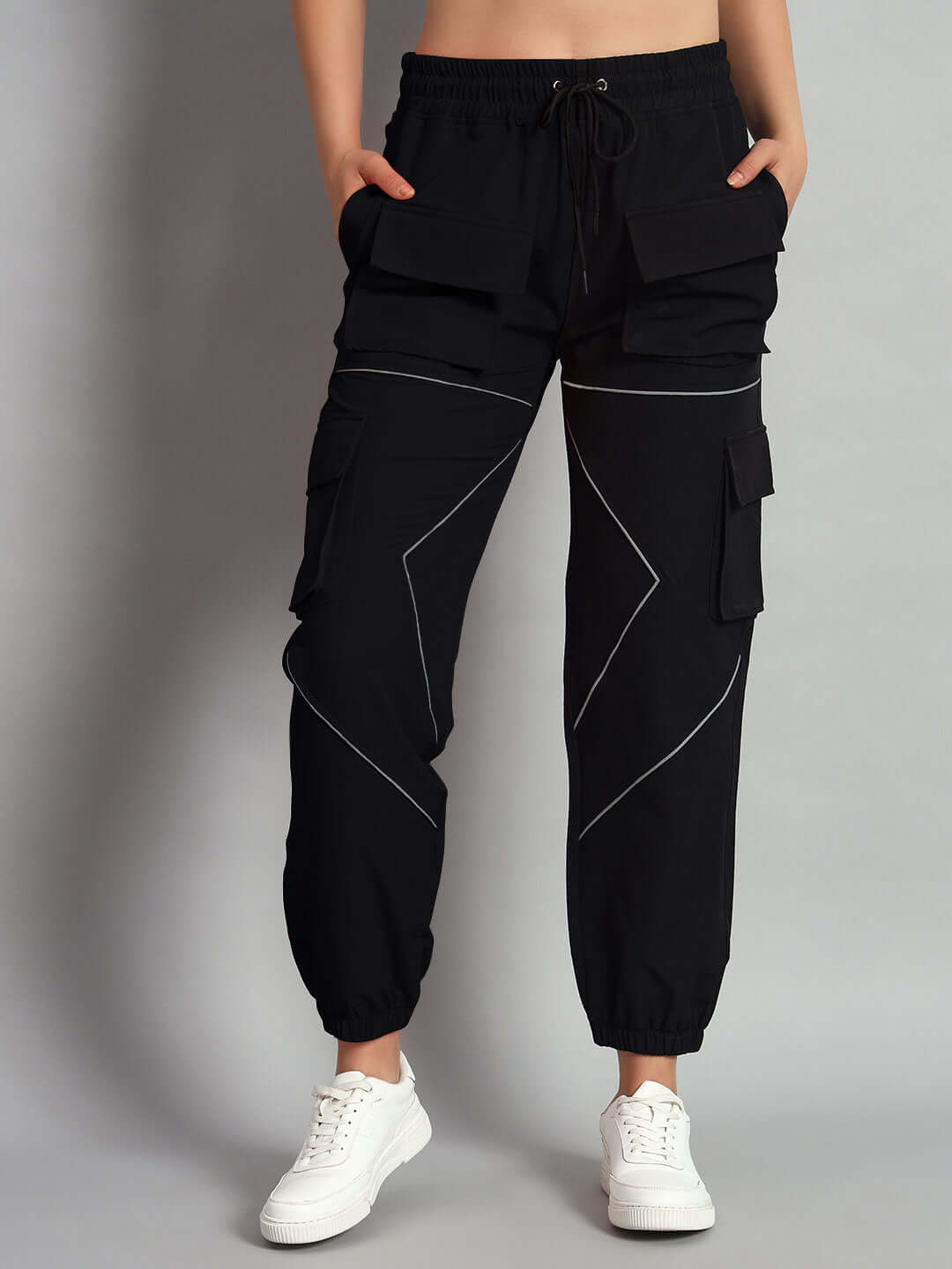 Women's black parachute cargo pants with reflective details, featuring multiple pockets, modeled with sneakers.