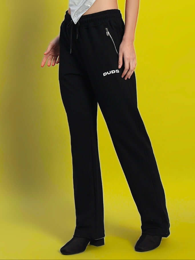 Woman wearing black relaxed fit jogger pants by DUDS against a yellow background