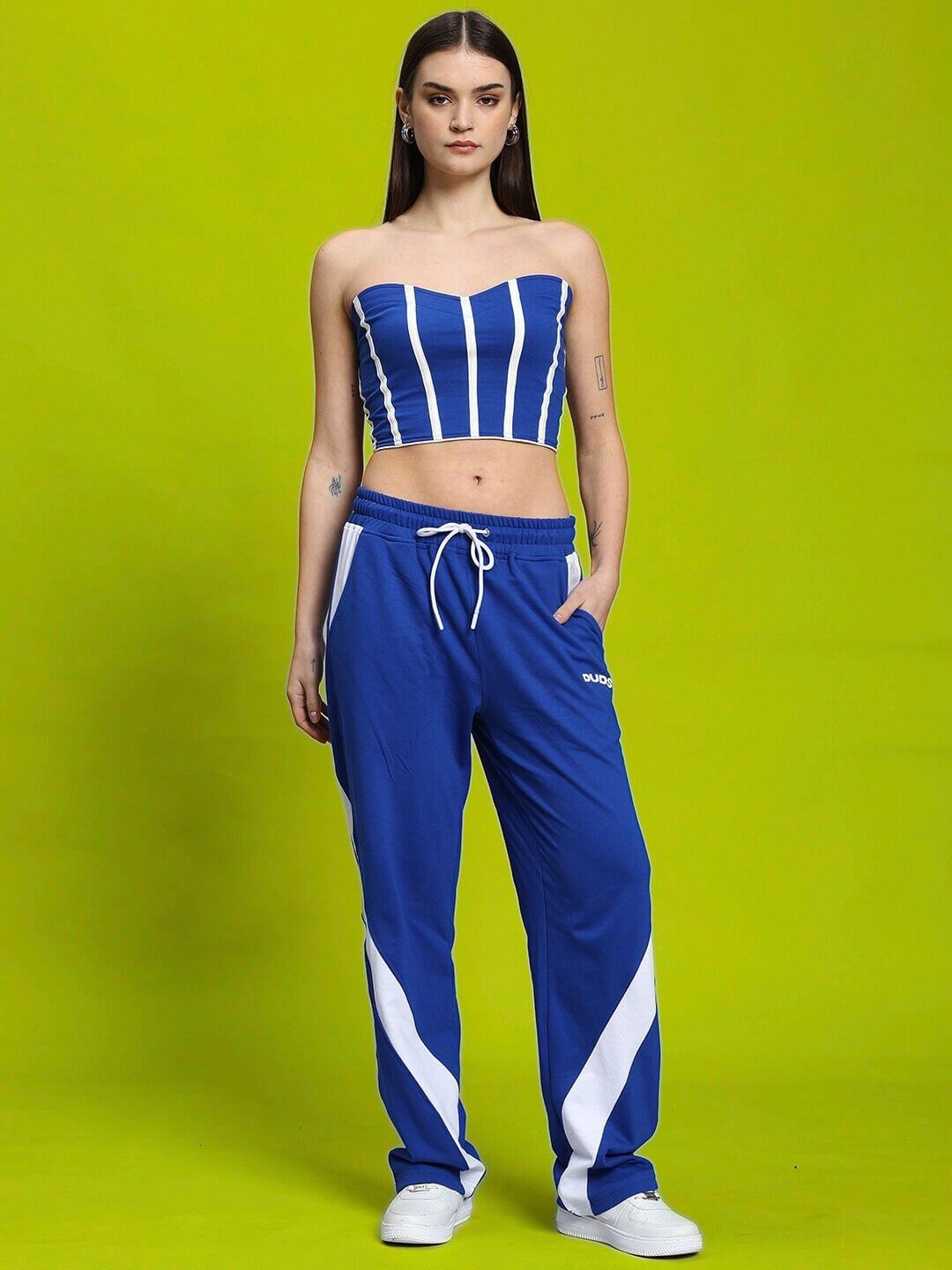 Woman wearing WOMEN'S LIVIANA COOL CO-ORD SET BLUE-WHITE by WEAR DUDS on a green background, showcasing stylish streetwear fashion.
