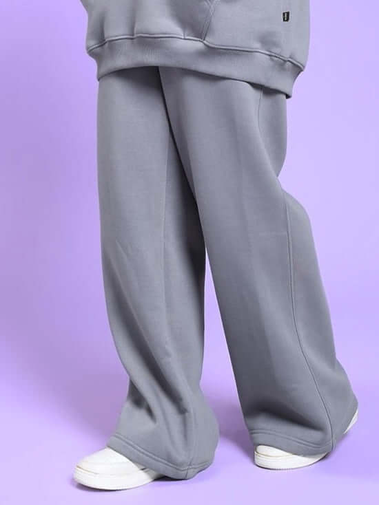 Woman wearing WOMEN'S MAKE IT HAPPEN COTTON FLEECE JOGGER GREY with sneakers, purple background.