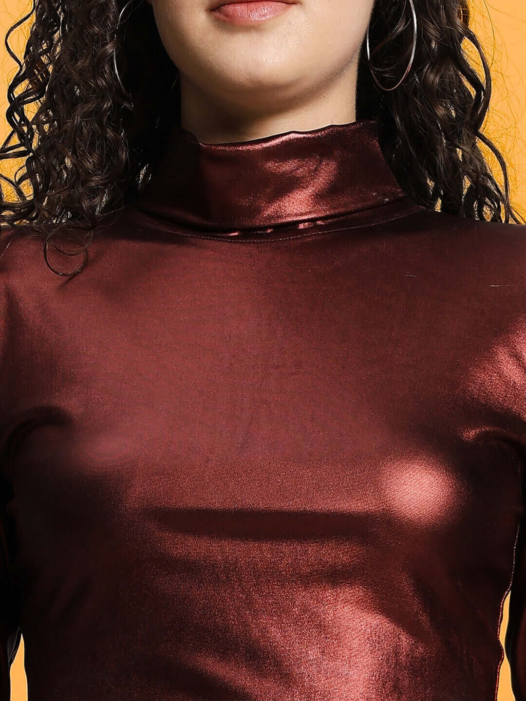 Close-up of a woman wearing a maroon metallic crop top.