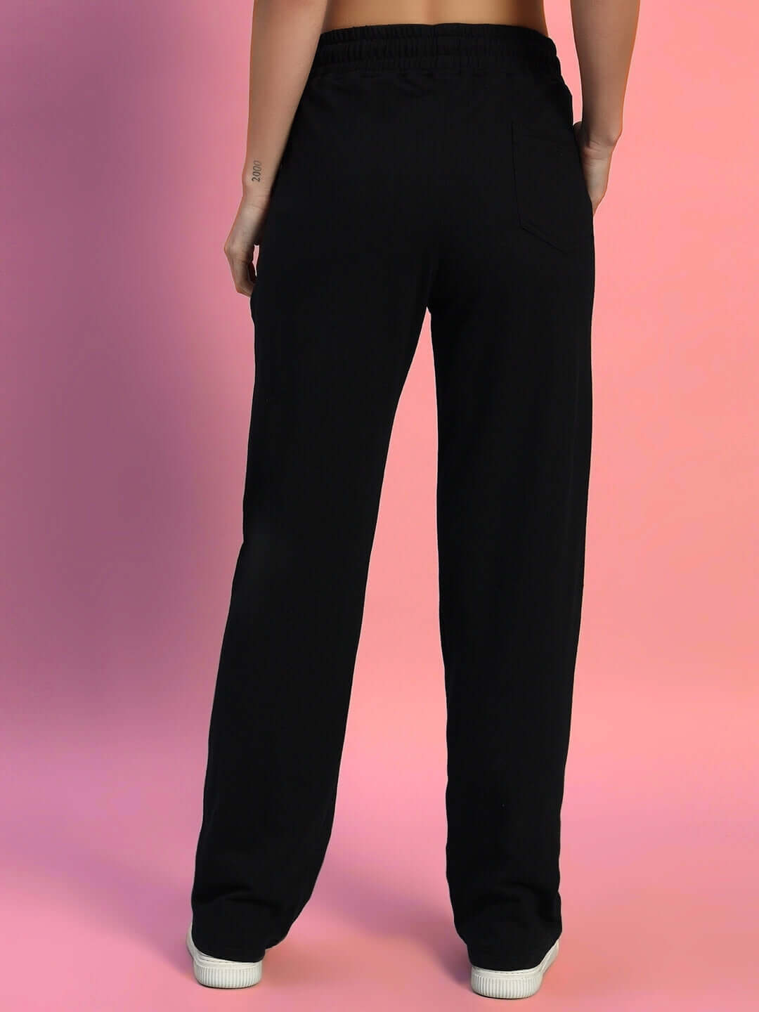 Back view of women's black 2 stripe jogger pants by DUDS, showcasing elastic waistband and comfortable fit, against a pink background.