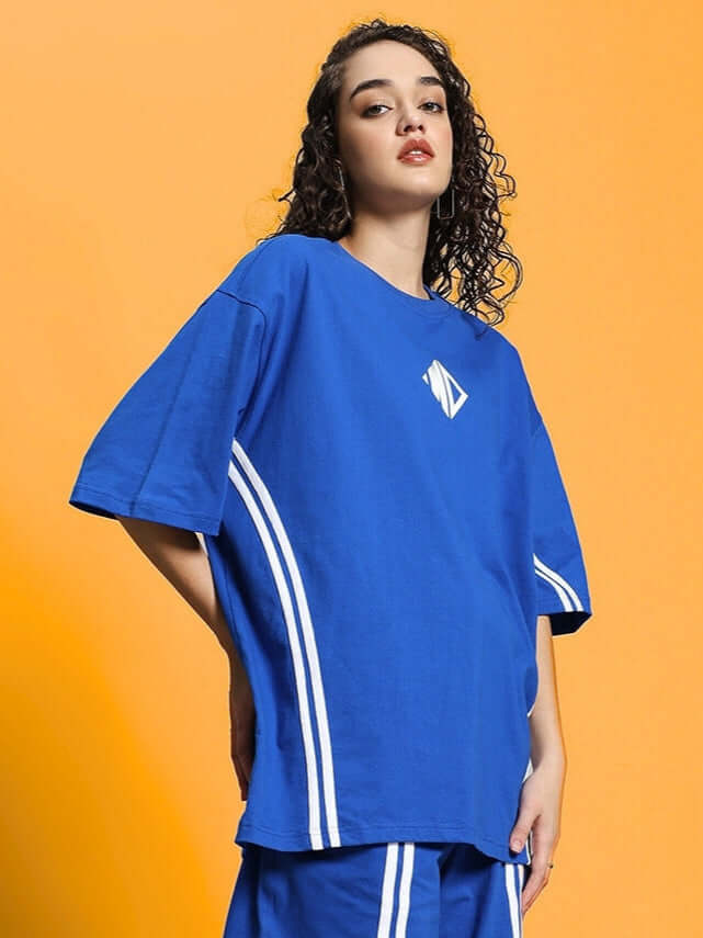 Woman wearing oversized blue t-shirt with white stripes, made from premium cotton blend fabric. Fashion forward and comfortable design.