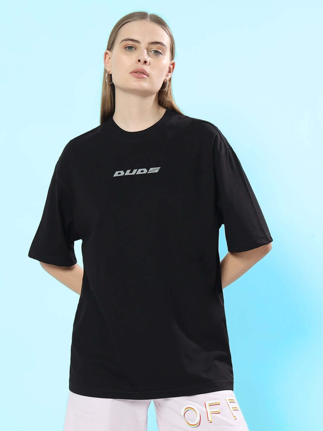 Model wearing black oversized women's T-shirt with 'Duds' logo, made of premium cotton and elastane, against a light blue background.