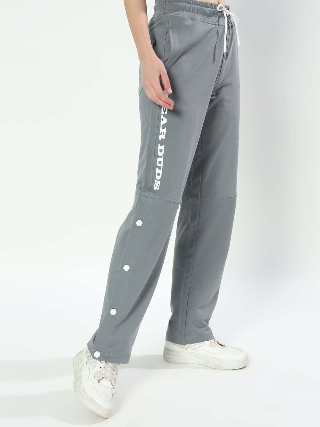 Women's grey racer joggers by DUDS with side branding and button detail, shown with white sneakers. Perfect for custom fit orders.