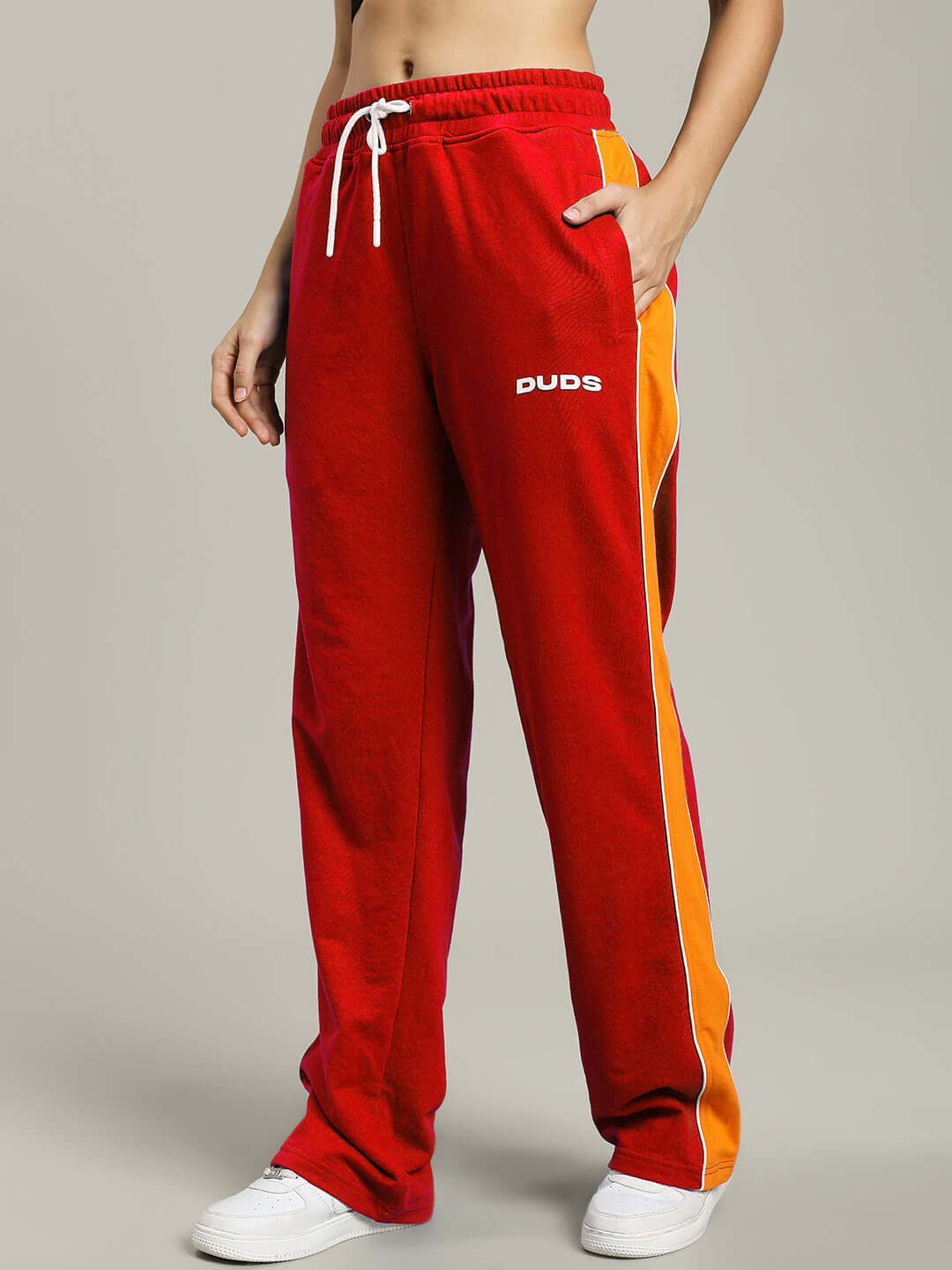 Woman wearing red Women's Sanford Stripe Joggers by DUDS, featuring white drawstring and side stripes. Perfect for casual wear.