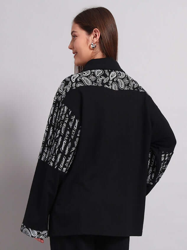 Back view of a woman wearing a black Sanganeri shirt with intricate patterns, showcasing handmade craftsmanship by skilled tailors.