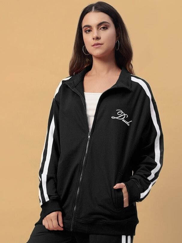 Woman wearing black women's Scotia jacket by DUDS, featuring a zip-up front and white stripe detail on sleeves.