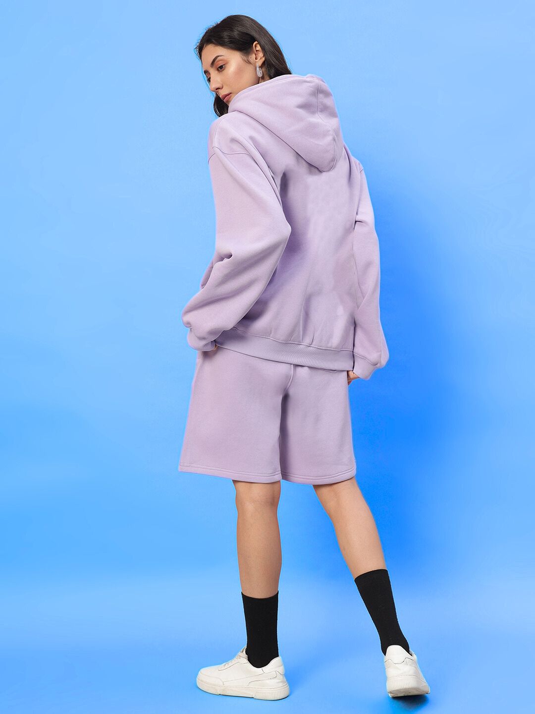 Woman wearing WOMENS SILENT HUG PRINTED FLEECE CO-ORD LILAC in pastel lilac, showcasing cozy street style against blue backdrop.