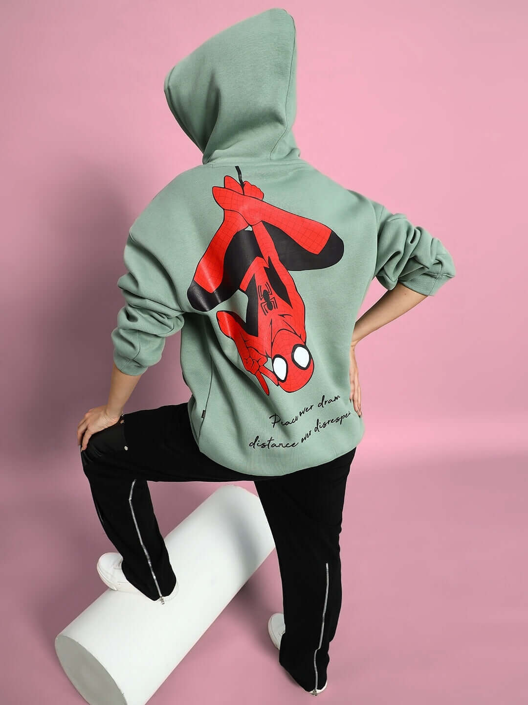 Back view of model wearing WOMEN SPIDERMAN OVERSIZED FLEECE HOODIE JADE GREEN with Spiderman graphic on pink background