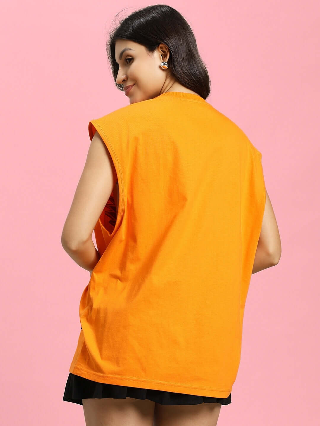 Back view of a woman wearing an orange Super Saiyan gym t-shirt, showcasing sleeveless design and comfort fit against a pink background.