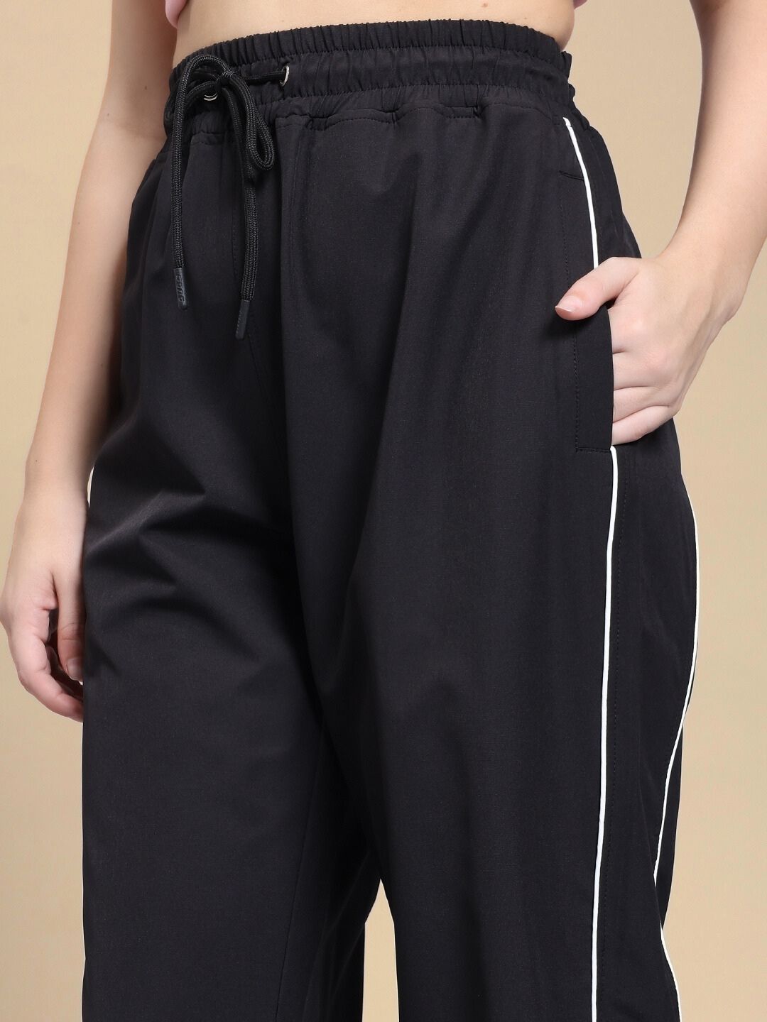 Close-up of WOMEN TURBO TRACK RELAXED-FIT JOGGERS BLACK, showcasing elastic waistband and side piping detail for sporty style.