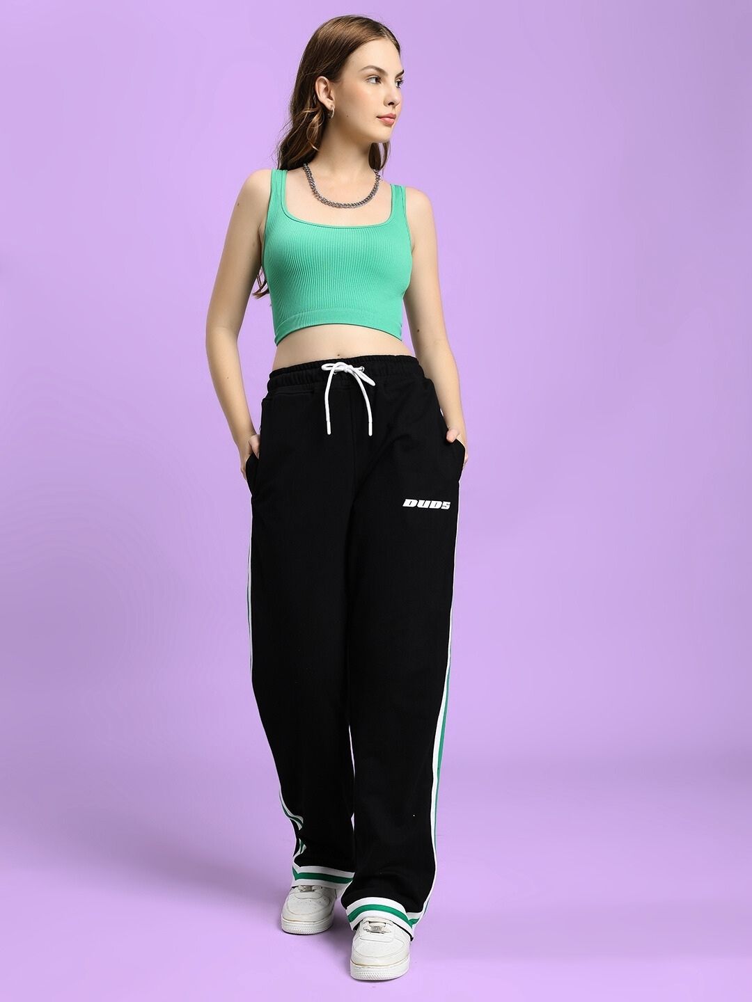 Woman wearing WOMEN'S VELO GREEN STRIPE RELAXED FIT JOGGER BLACK on a purple background with matching top.