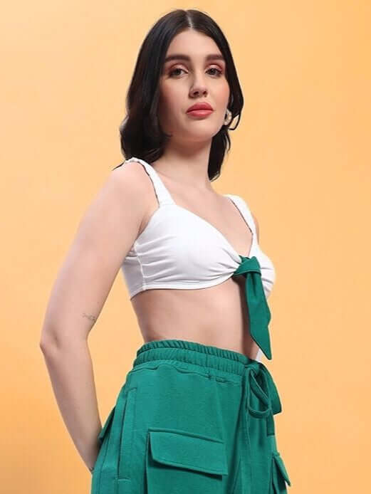 Woman wearing a stylish white crop-top paired with teal cargo pants, set against a peach background.