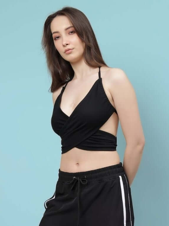 Woman wearing a black criss cross crop-top with a stylish design, made from premium heavy gauge cotton fabric.