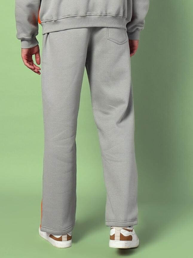 Man wearing grey colorblock co-ord set from DUDS, featuring relaxed fit pants and sneakers, back view.