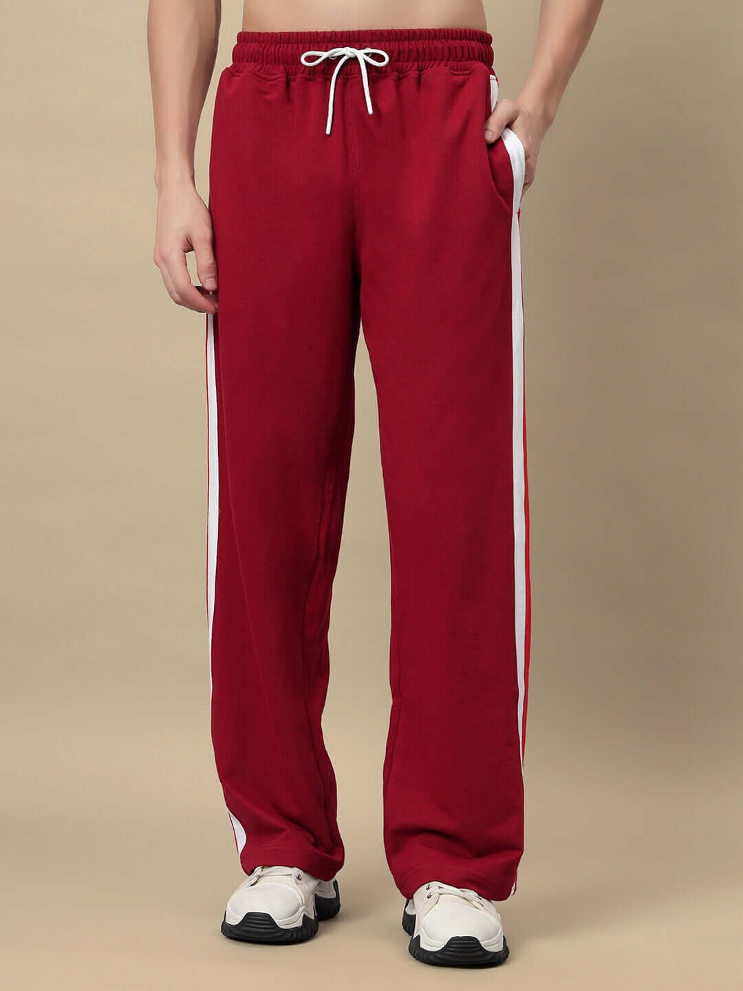 Men's maroon jogger pants by ZEST with white side stripes, modeled on a beige background, featuring drawstring waist and side pockets.
