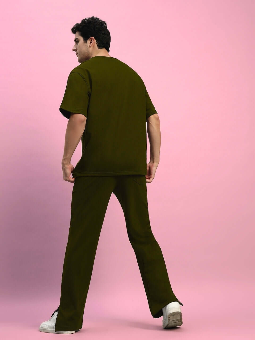 Model wearing ZION Relaxed Fit Co-Ord Set in olive green, featuring a premium unisex design with joggers and a t-shirt, against a pink background.