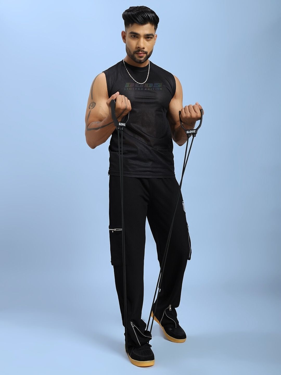 Man wearing ZIP TECH PREMIUM CARGO IN BLACK using resistance bands, showcasing stylish utility pants for urban adventures.