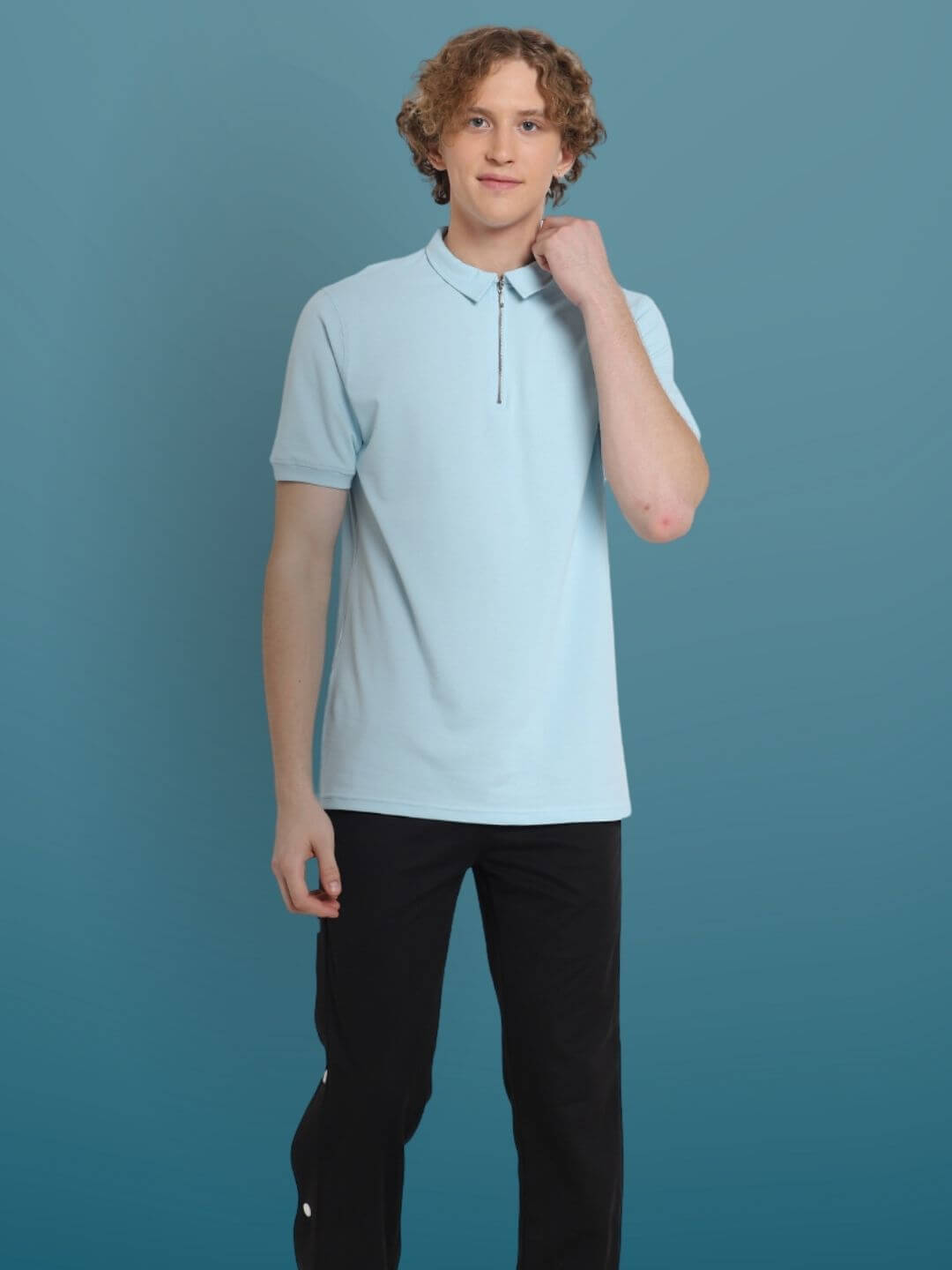 Young man wearing a powder blue zipper polo neck t-shirt made from sporty pique cotton with superior stretch and wrinkle-free fabric.