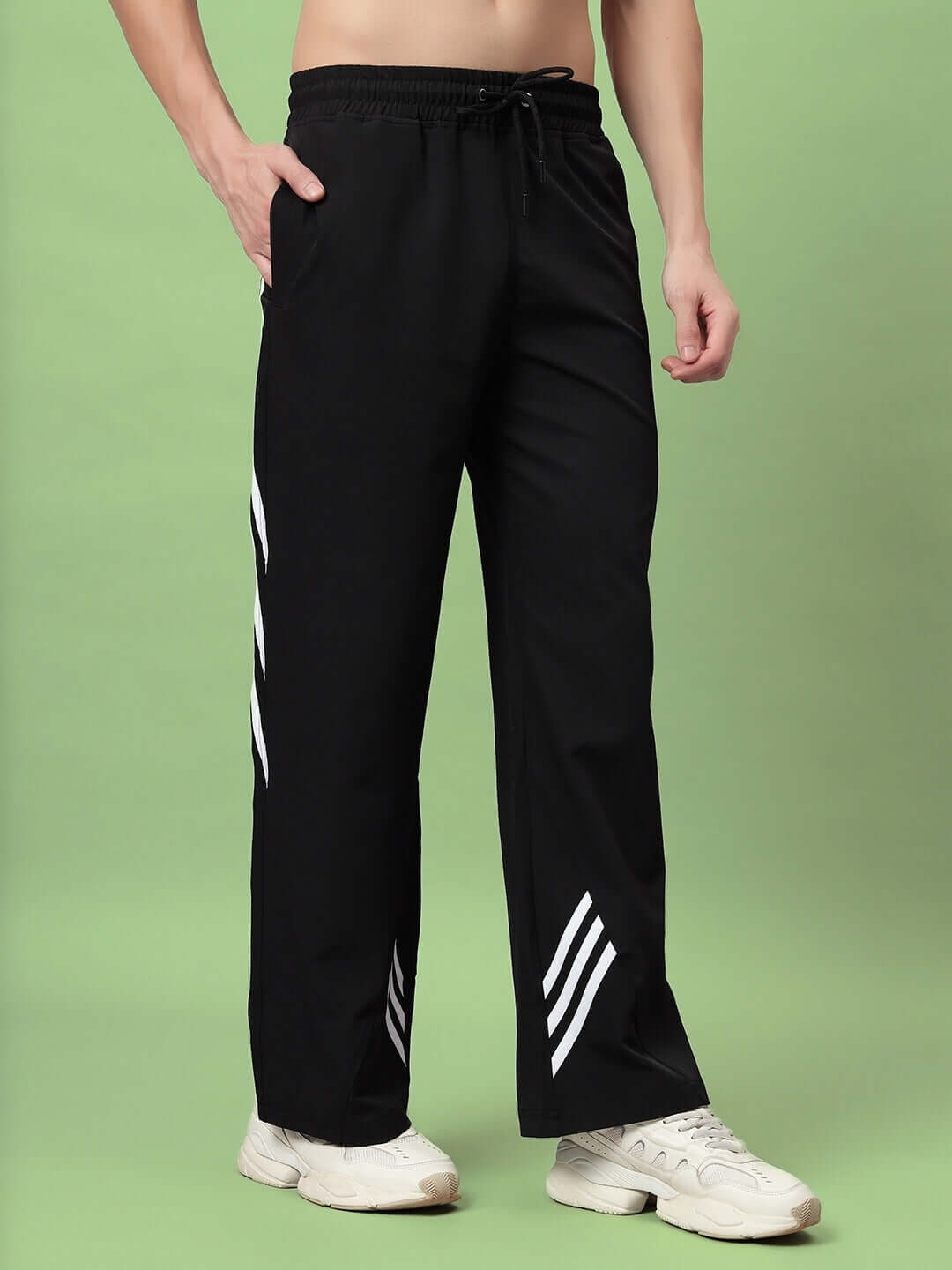 Person wearing black Zoomer relaxed fit cargo pants with side pockets and adjustable waist, styled with white sneakers on a green background.