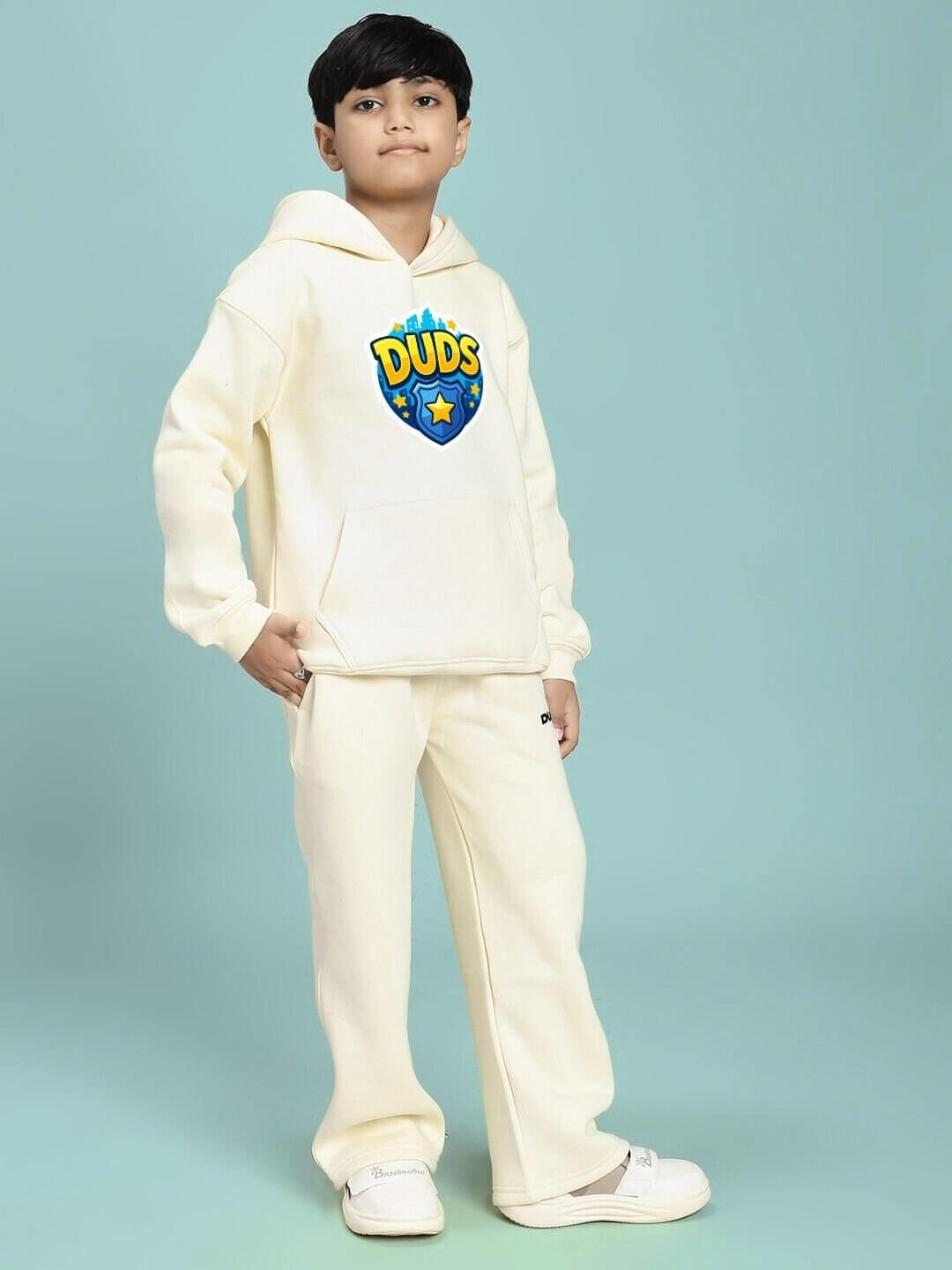 Child wearing ZOOTOPIA WORLD FLEECE CO-ORD FOR BOYS AND GIRLS OFF WHITE against a blue background, showcasing cozy and stylish outfit.