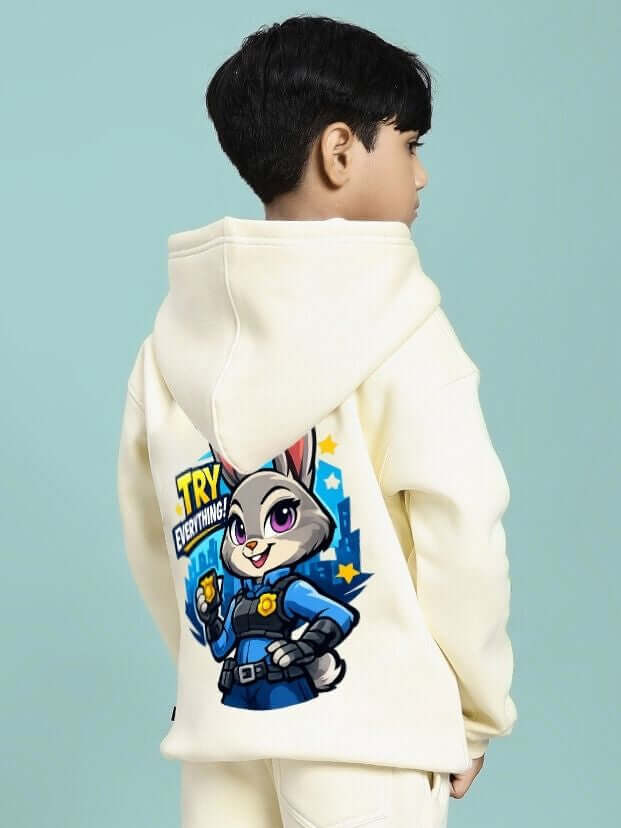 Child wearing ZOOTOPIA WORLD FLEECE HOODIE FOR BOYS AND GIRLS OFF WHITE with cartoon character print on back.