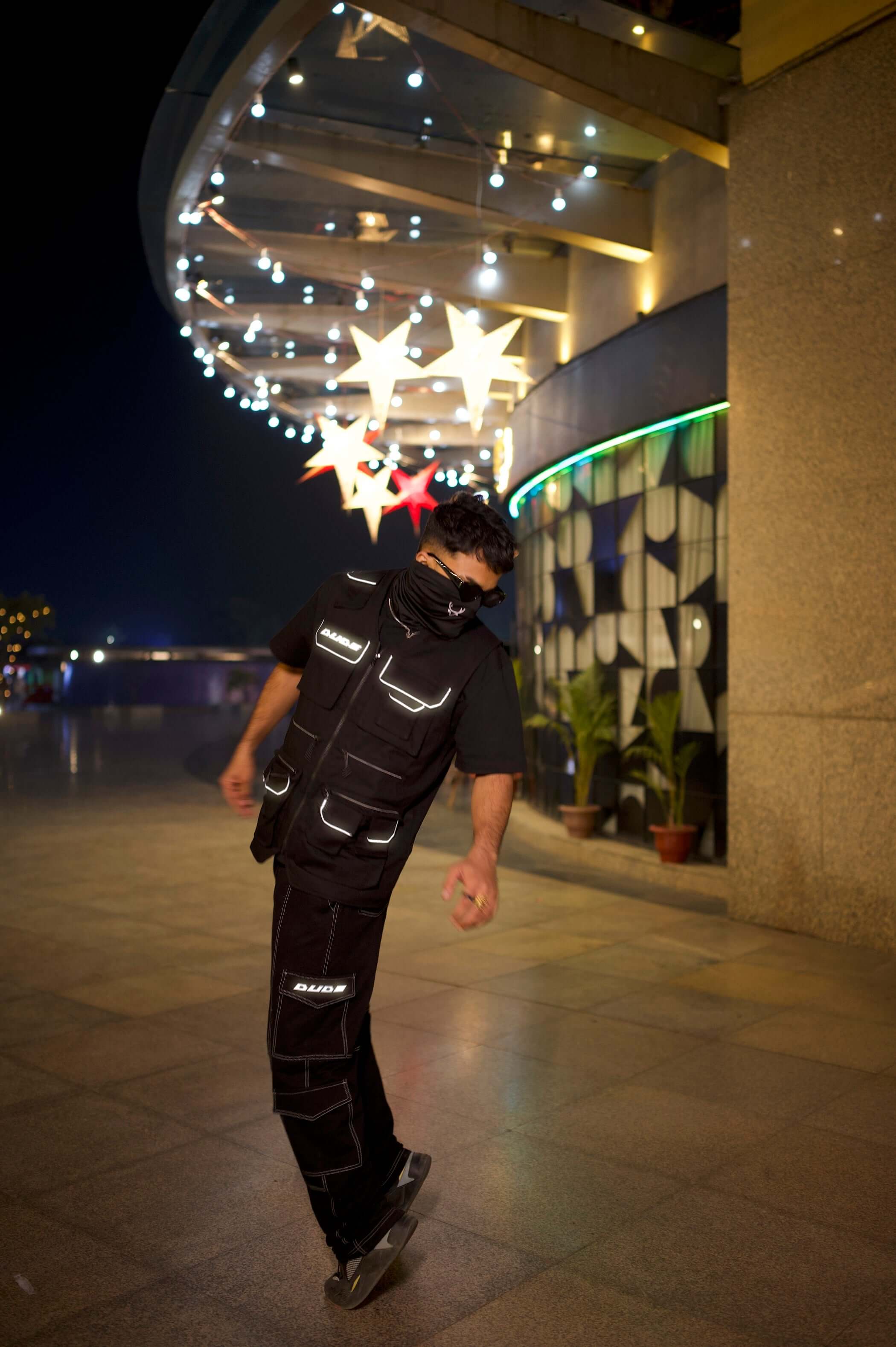 Man wearing MULTI POCKETS REFLECTOR CARGO VEST in urban night setting, highlighting utility and modern streetwear style.